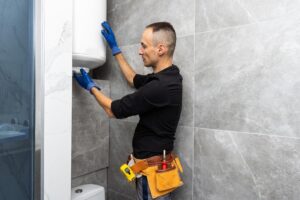 A man fitting components in a remodelled bathroom.